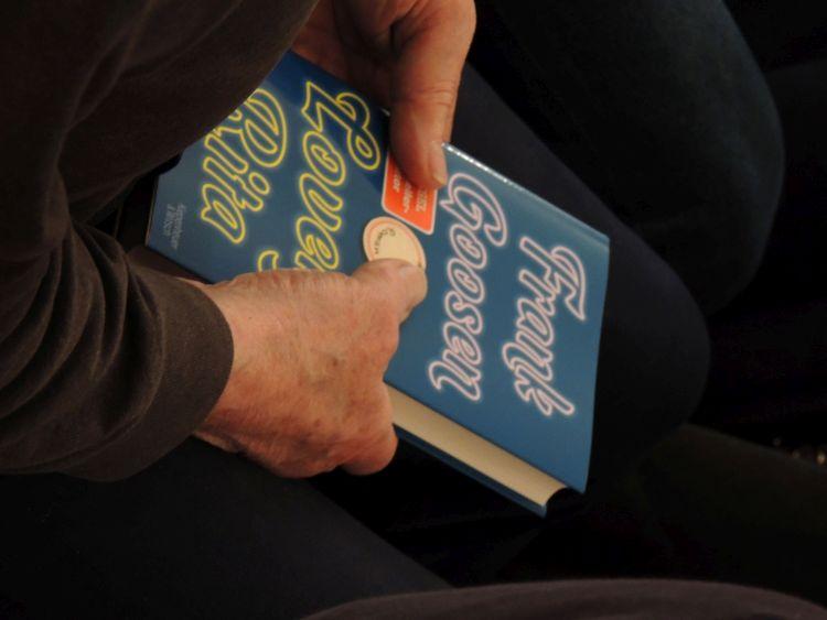 Ein Zuschauer hält das signierte Buch in der Hand